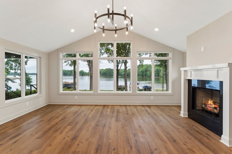 Modern light fixture above wood flooring in living room with windows surrounding the room in custom home renovation by PAXISgroup