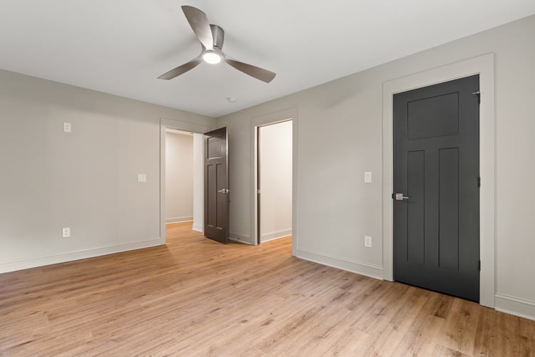 Bedroom with wood flooring and ceiling fan in custom home remodel by PAXISgroup