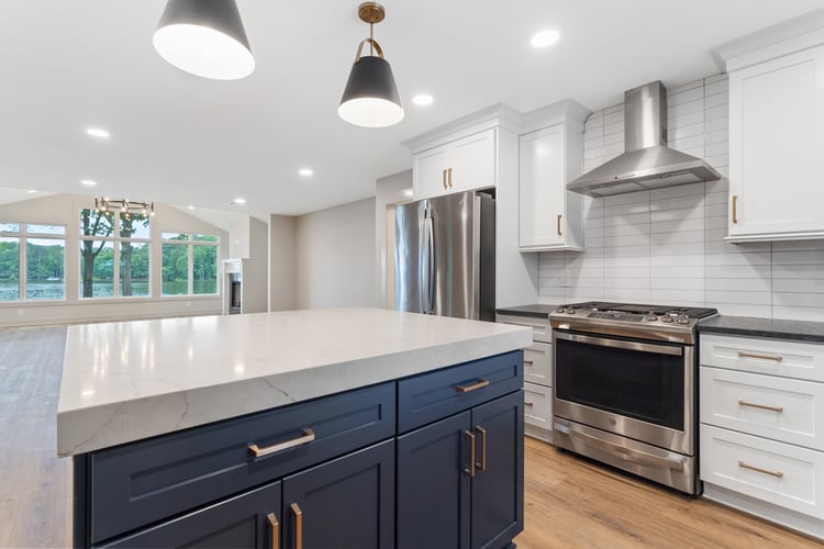 Kitchen island with white countertop and blue cabinets in modern kitchen by PAXISgroup